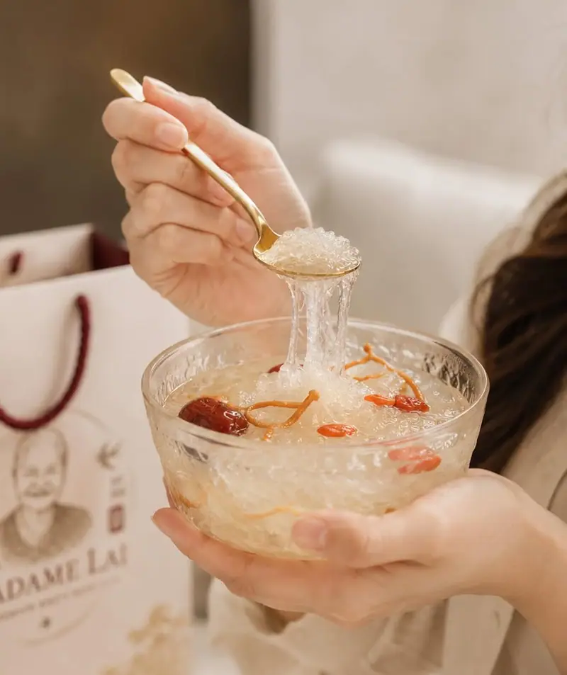 A spoonful of prepared bird's nest lifted from a glass bowl